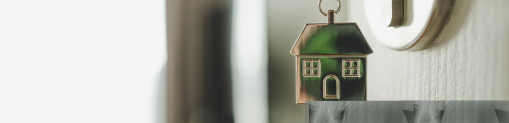 Open the door and door handle with a key and a keychain shaped house. Property investment and house mortgage financial real estate concept